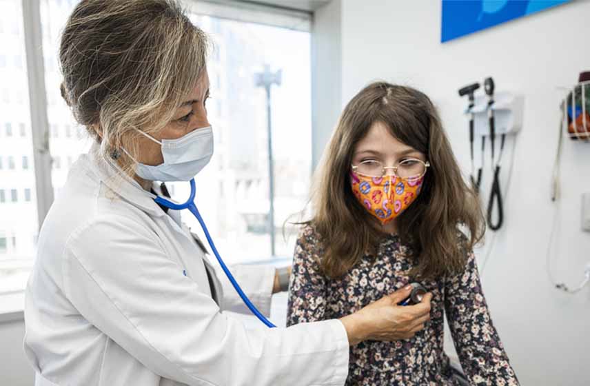 Doctor examining child's breath sounds with a stethoscope.