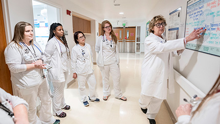 Caregiver reviewing info on whiteboard with clinical students.