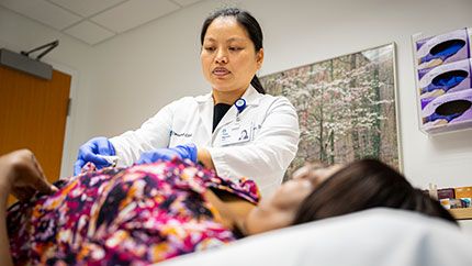 Dr. Thuy Nguyen, DAOM, Lac providing acupuncture for a patient.
